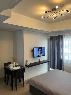 a bedroom with a table and a tv on the wall at Condotel 1 Bedroom Across SM Aura in Manila
