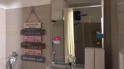 a bathroom with signs on the wall next to a mirror at TresMaria'Staycation in Manila