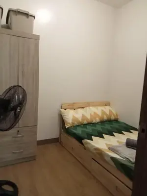 a bedroom with a bed with a fan and a dresser at SM HOME Spring Residences Staycation and Condotel in Manila