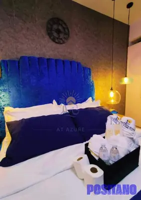 a bed with a blue head board with water bottles on it at Oveecation Suites Positano Smarthome in Manila