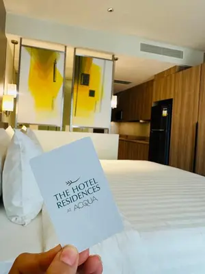 a person holding a piece of paper on a bed at Hotel Residences near Makati in Manila