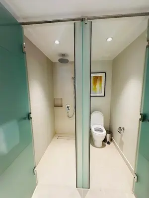 a bathroom with a toilet and a glass door at Hotel Residences near Makati in Manila