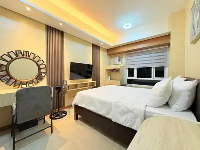 a bedroom with a bed and a mirror and a television at Makati Beacon Studio Suite in Manila