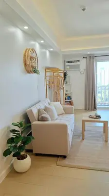 a living room with a white couch and a plant at Luxury Bohemian Suite Venice Canal Mall & BGC Views in Manila