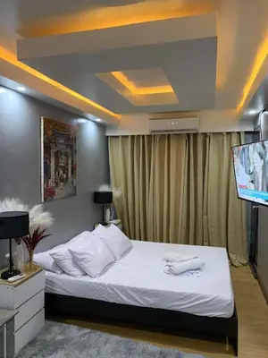 a bedroom with a bed with a flat screen tv at Aura Suites in Imus