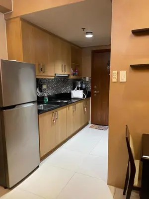 a kitchen with wooden cabinets and a stainless steel refrigerator at Cozy Staycation by Ayumi in Manila