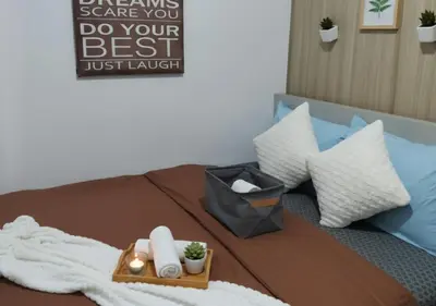 a bed with a tray of towels and a sign on it at Heart of Mall of Asia - Aseana Pasay in Manila
