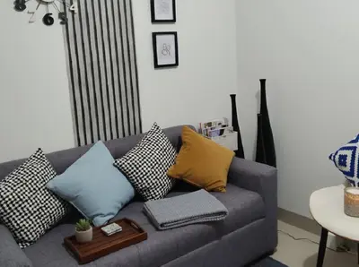 a living room with a gray couch with pillows at Heart of Mall of Asia - Aseana Pasay in Manila