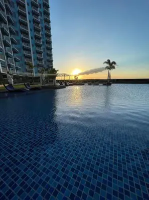 a large swimming pool with a sunset in the background at Luxury 1BR beside Okada Manila in Manila