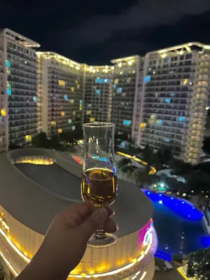 a person holding a glass of wine on a balcony at M&M Azure Staycation Parañaque in Manila