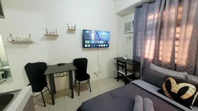 a living room with a bed and a table and a tv at Richard's Pad in Manila