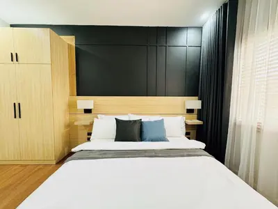 a bedroom with a large bed and a black wall at MUJI TOWNHOUSE SUITE in Central Makati BILLIARDS, KTV in Manila