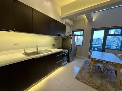 a kitchen with a sink and a table with a dining room at Newly Renovated 2-Storey Loft at Greenbelt 1 in Manila