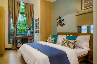 a bedroom with a bed and a desk and a window at Vintage Mickey Disney Stay in BGC -200mbps wifi in Manila