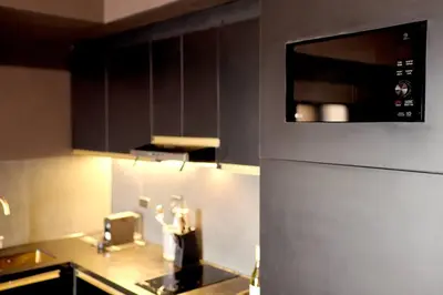 a kitchen with black cabinets and a counter top at Italian Style Unit in Venice Luxury Residences in Manila