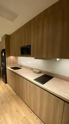 a kitchen with wooden cabinets and a sink and a refrigerator at The Metro Zen at Hotel Residences Acqua - Novotel Tower in Manila