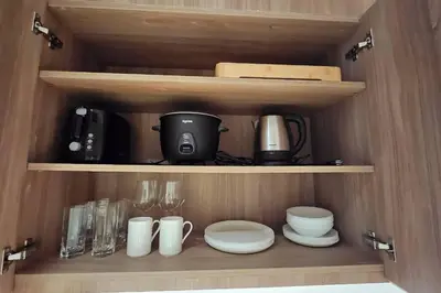 a cupboard with plates and cups and utensils at The Metro Zen at Hotel Residences Acqua - Novotel Tower in Manila