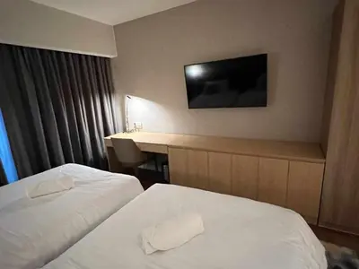 a hotel room with two beds and a desk at The Metro Zen at Hotel Residences Acqua - Novotel Tower in Manila