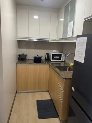 a kitchen with white cabinets and a sink and a microwave at Gentry Manor Balcony Green View WiFi Netflix Walk to Okada Casino 8J in Manila