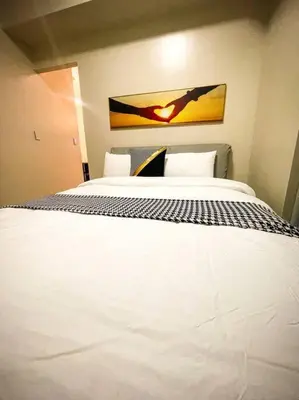 a bedroom with a white bed with a painting on the wall at Luxury 1 Bedroom across Okada II Balcony w View in Manila