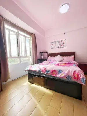 a bedroom with a large bed with pink sheets at Jennie's 5m Suite in Manila