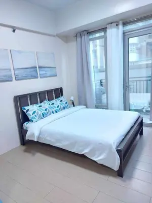 a bedroom with a large bed and a large window at Jennie's 5m Suite in Manila