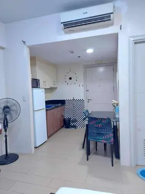 a kitchen with a table and a refrigerator at Jennie's 5m Suite in Manila