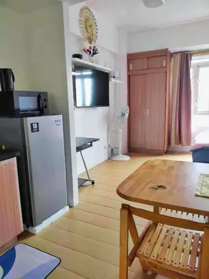 a living room with a table and a refrigerator at Jennie's 5m Suite in Manila