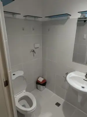 a white bathroom with a toilet and a sink at Alley condotel Sea Residence in Manila