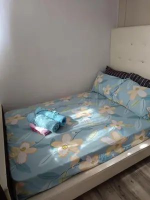 a bed with a blue blanket with flowers on it at Alley condotel Sea Residence in Manila