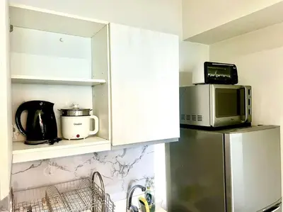 a kitchen with a microwave on top of a refrigerator at Azure South Bicutan spacious 1BR BEST view in Manila