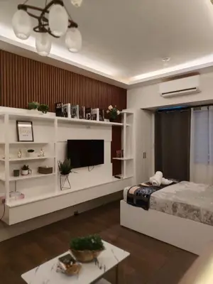 a living room with a bed and a television at Affordable Modern Studio with Netflix WiFi Balcony in Air Residences in Manila