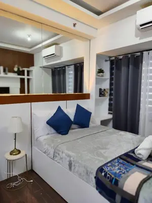 a bedroom with a large bed with blue pillows at Affordable Modern Studio with Netflix WiFi Balcony in Air Residences in Manila