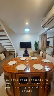 a living room with a table and a tv at Tahanan - Victoria de Makati in Manila