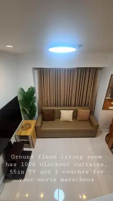 a living room with a couch in front of a curtain at Tahanan - Victoria de Makati in Manila
