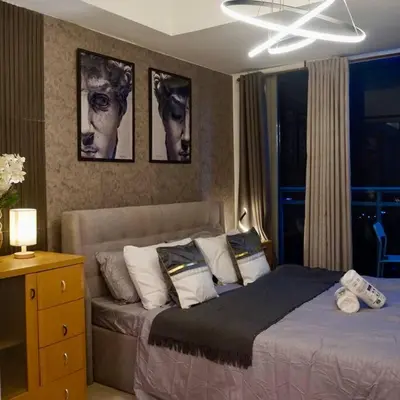 a bedroom with a bed and some pictures on the wall at Gabila Staycation at Azure in Manila