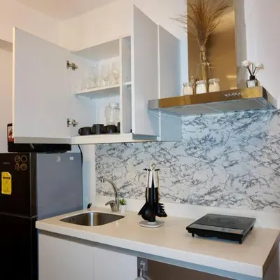 a kitchen with white cabinets and a sink and a refrigerator at Gabila Staycation at Azure in Manila