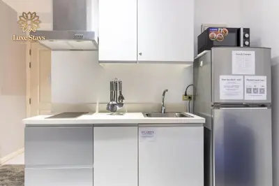 a white kitchen with a sink and a refrigerator at Affordable Staycation with Balcony at The Gramercy Makati in Manila