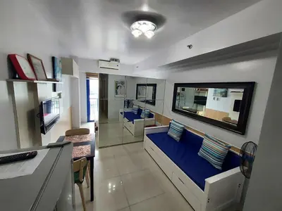 a living room with a blue couch and a kitchen at Great Stay in Manila in Manila