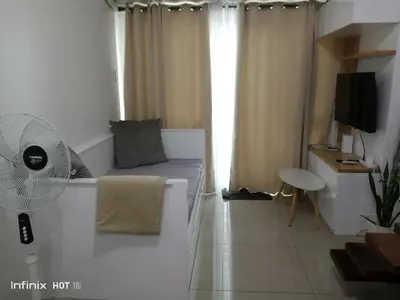 a living room with a couch and a fan at 1bedroom LOFT with Garden Terrace pool access in Manila