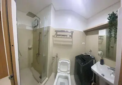 a bathroom with a shower and a toilet and a sink at Lush Suite Makati in Manila