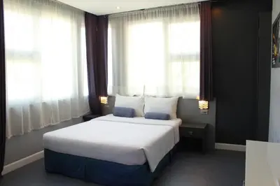 a bedroom with a large white bed with windows at Leez Inn Malate in Manila