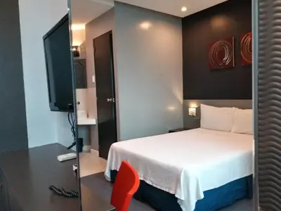 a hotel room with a bed and a television at Leez Inn Malate in Manila