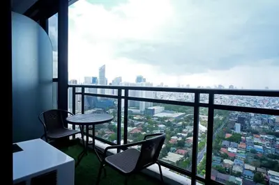 a table and chairs in a room with a view of a city at Spacious and Cozy 2 Br in The Gramercy Poblacion in Manila