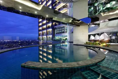 a hotel swimming pool with a city skyline at night at Spacious and Cozy 2 Br in The Gramercy Poblacion in Manila