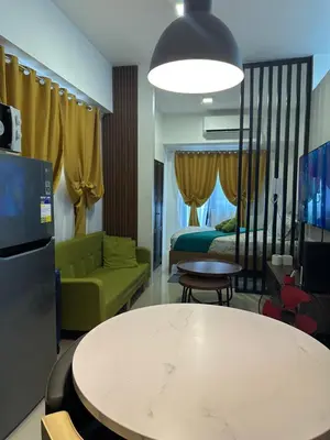 a living room with a couch and a table and a bed at Cozy 2BR Unit in FAME Residences, Mandaluyong City in Manila