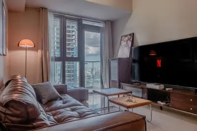 a living room with a leather couch and a large window at Parksuites BGC - Spacious 2 Bedroom in Manila