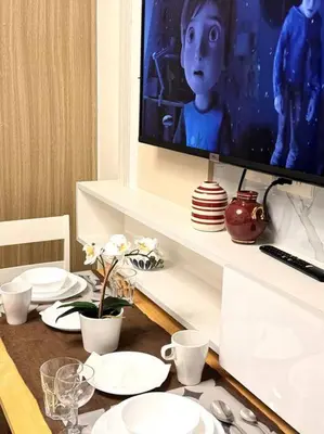 a dining room table with white plates and a tv at Daisy's Suite by Staycation in Manila
