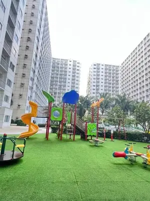 a playground in a park with tall buildings at Daisy's Suite by Staycation in Manila