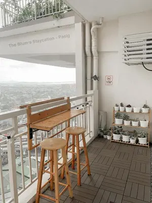 a balcony with a wooden table and two stools at 2BR The Blums at Prisma Residences in Manila